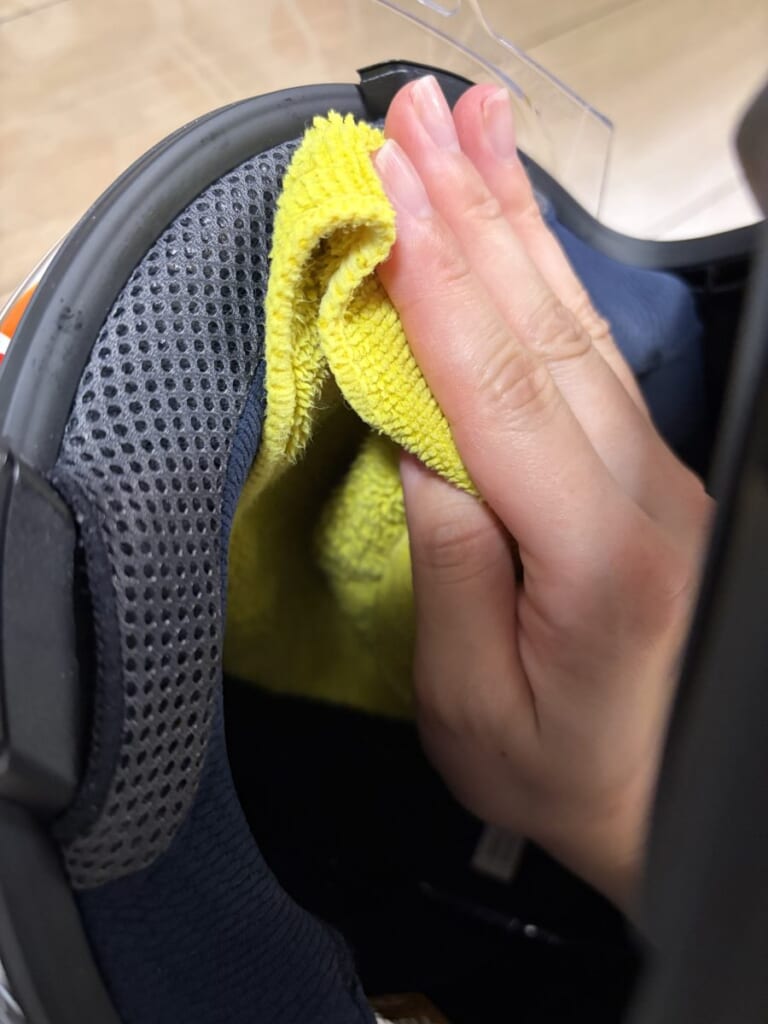 ヘルメットの内側を布で拭いている手元